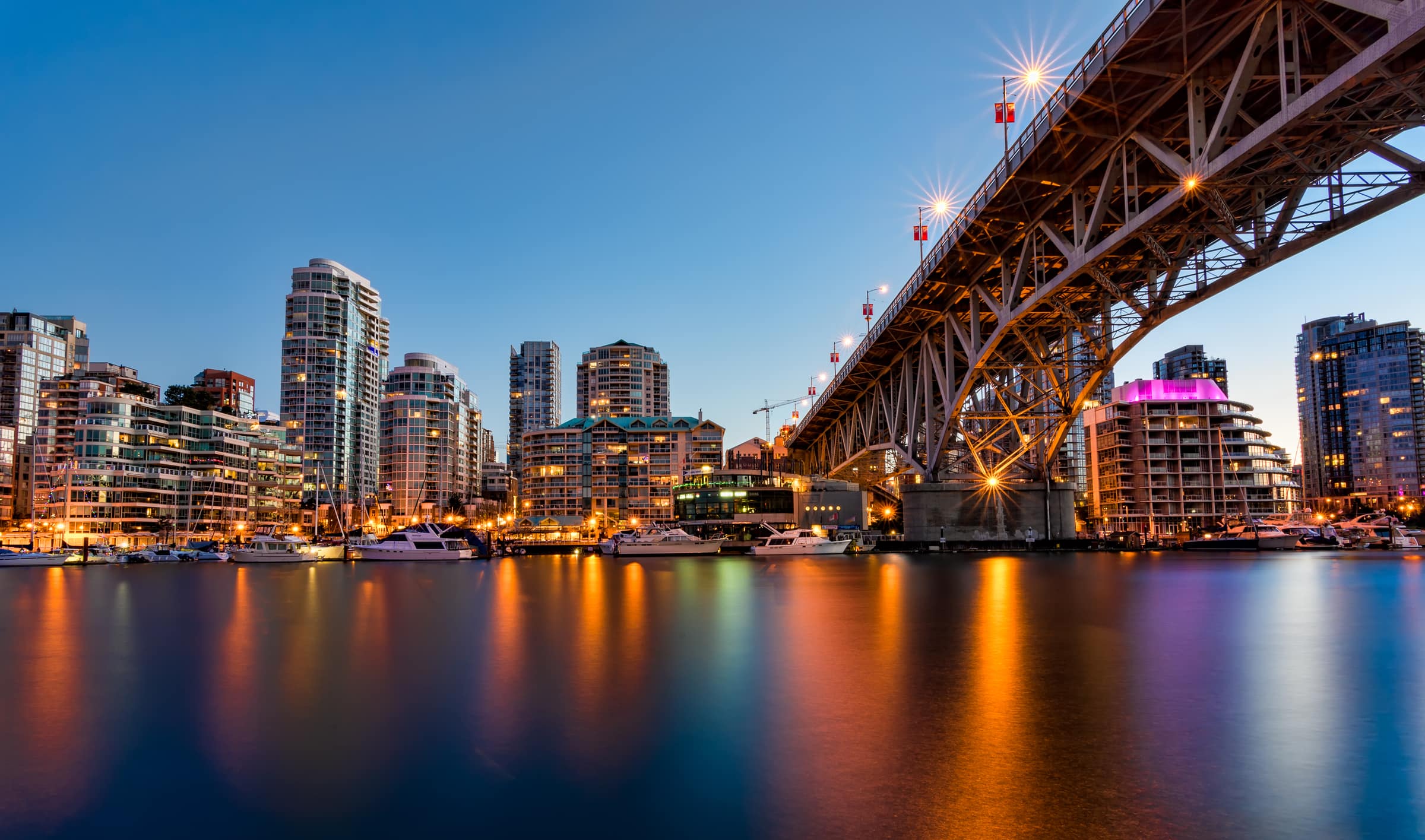 Granville Street Bridge and the False Creek marina at dusk, with the Vancouver skyline behind